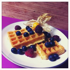 Ein Teller mit zwei Waffeln und Waldbeeren.