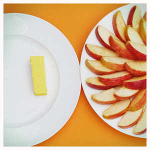 Links ein Teller mit einem Stück Butter, rechts ein Teller mit Apfelstücken