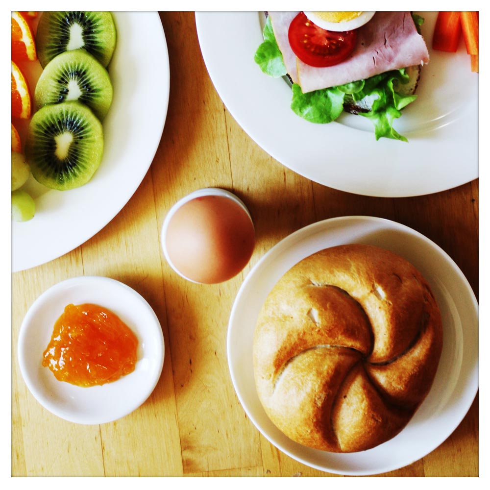 Dieser Beitrag erklärt, was der Süßstoff Saccharin E954 ist. Auf dem Beitragsbild sieht man ein Frühstücksei, Marmelade, eine Semmel, ein mit Salat, Schinken, Tomaten und Ei belegtes Brot sowie Kiwi- und Orangenscheiben.